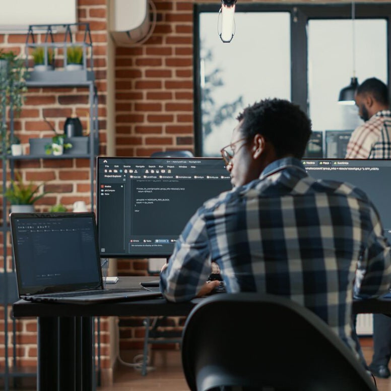 Man seated at a desk, looking at the laptop
