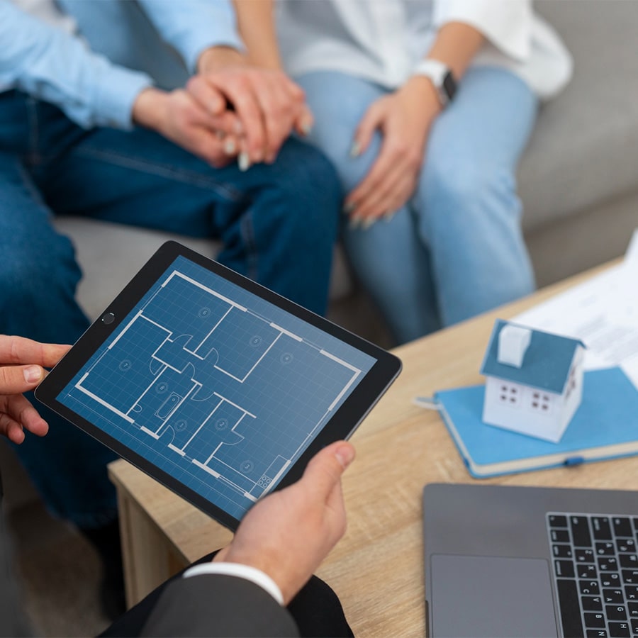 Tablet displaying the house plan and a couple sitting on a couch holding hands